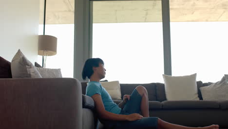 Teenage-Asian-boy-sits-comfortably-on-a-couch-at-home,-with-copy-space