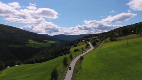 scenic aerial view of a winding road cutting through the lush, green hillsides of norway under a clear blue sky