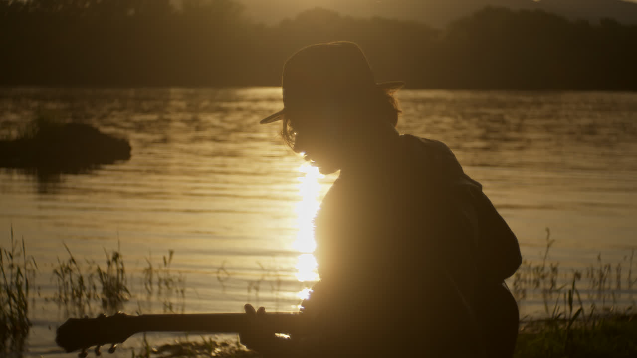 Silhouette of a Musician Playing Guitar at Sunset