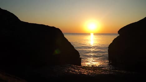 sunrise at the sea beyond rocks on the shore