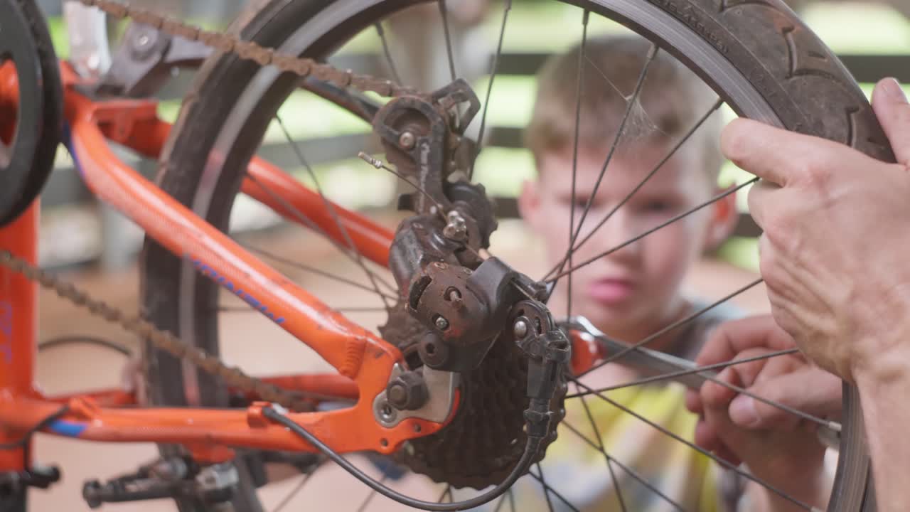 Pai e filho trabalhando juntos: o pai ensina o filho sobre ferramentas e conserta sua bicicleta. Clipe 7