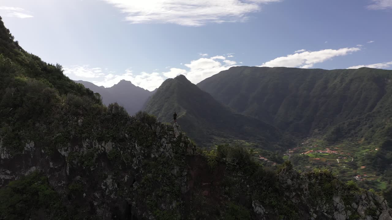 clip de dron circular de un hombre parado en el borde, rodeado de hermosa naturaleza en madeira