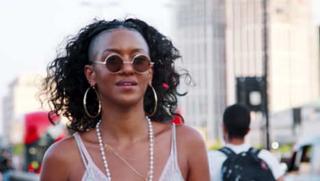 Fashionable-young-black-woman-walking-over-a-bridge-in-the-city,-close-up