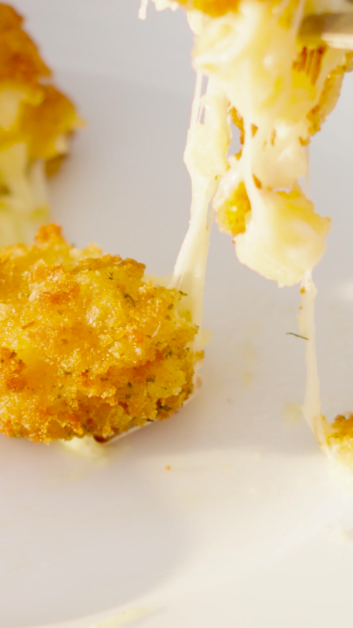 Vertical Video of Pasta Crispy Croquette with Stringy Cheese as Fork Picks Up Piece to Eat.