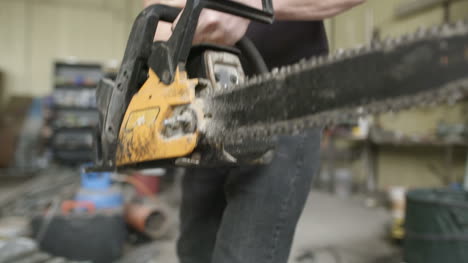 young craftsman starting powered chainsaw in workshop 2