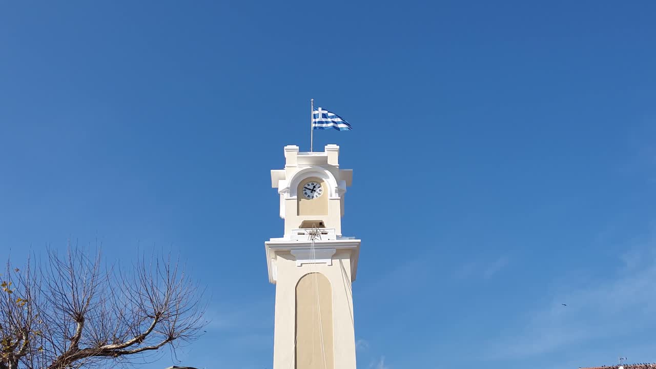 Clock Tower with Greek Flag in a Town
