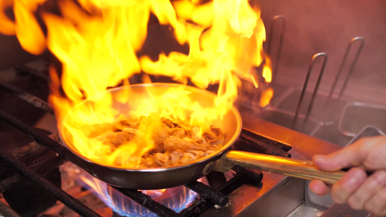 ragout flameado de chef experto en sartén en la cocina del restaurante, de cerca
