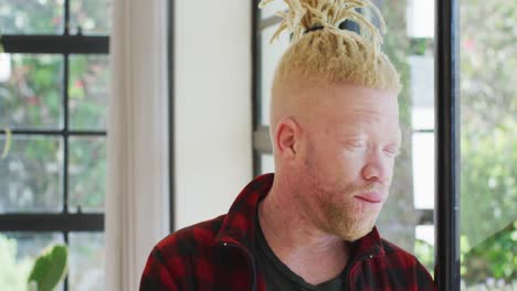 hombre albino afroamericano pensativo con rastas mirando por la ventana