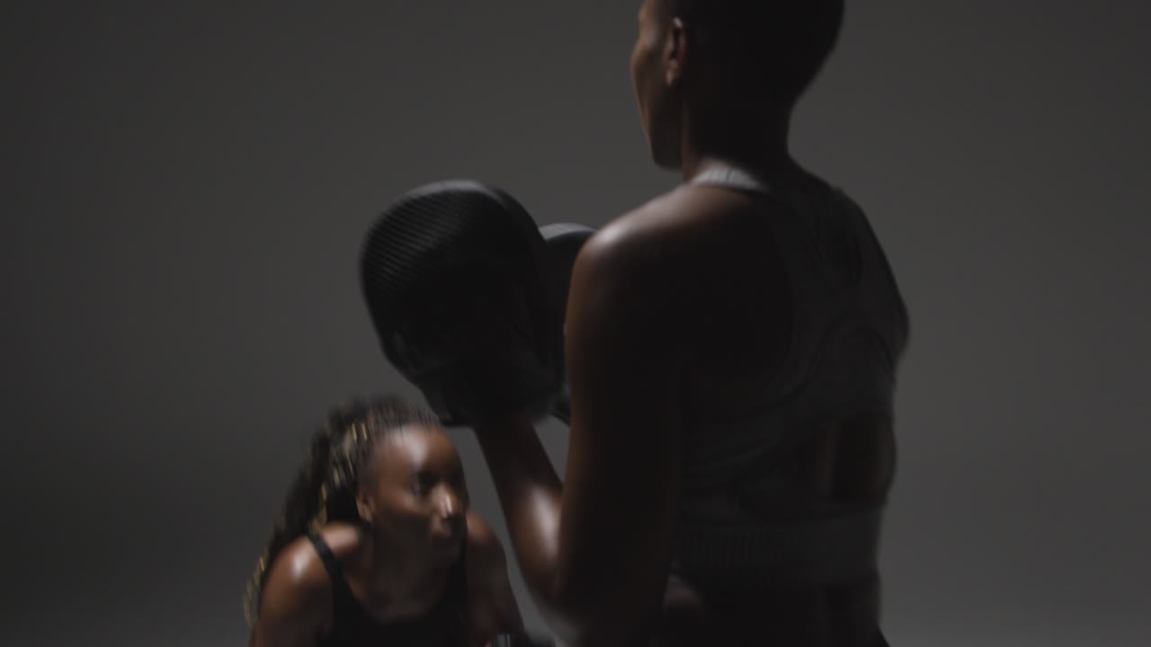 foto de estudio de una mujer con guantes de boxeo luchando con el entrenador 2
