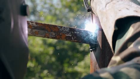 close view worker connects fence rail with welding machine