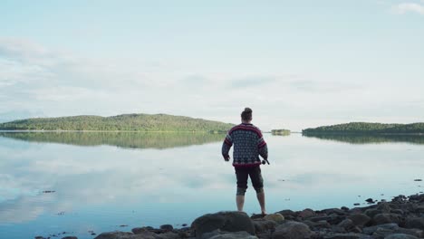 Un-Hombre-Pescando-En-El-Lago-Con-Reflejos-De-Espejo-Cerca-Del-Pueblo-De-Vangsvik-En-Senja-Noruega