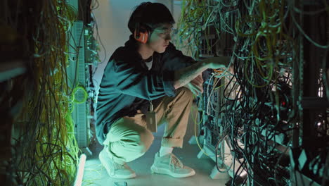 male asian system administrator fixing server wires