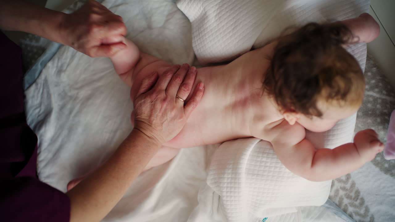 Bambino sdraiato sulla pancia mentre un adulto lo massaggia ed esegue esercizi di mobilità