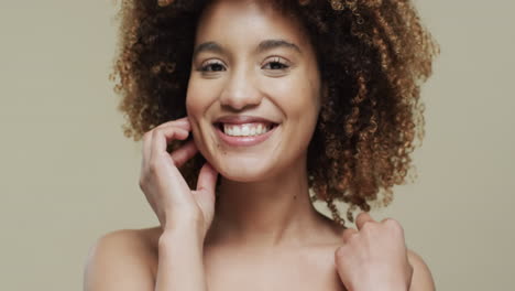 happy biracial woman with dark curly hair on beige background, slow motion