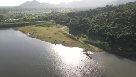 Imágenes-Aéreas-De-4k-Que-Vuelan-Sobre-El-Embalse-De-Khlong-Bod-Con-Luz-Solar-Reflectante-Sobre-El-Agua-Y-El-Fondo-Montañoso-En-Nakhon-Nayok,-Tailandia