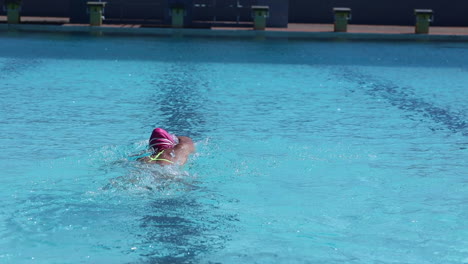 imágenes de una nadadora nadando vueltas en una piscina al aire libre usando la brazada de estilo libre como parte de su plan de entrenamiento de triatlón