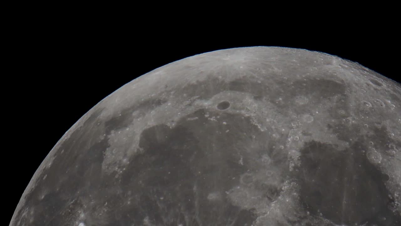 a super telephoto video of The giant full Moon passing through the night sky in space taken with a telescope