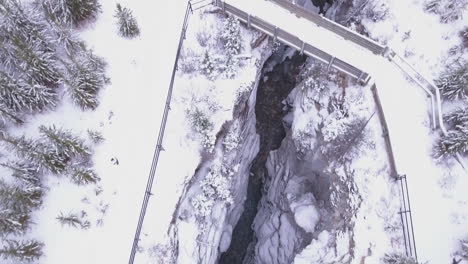 aerial: snowy bridge crosses deep winter marble canyon in rocky mtns
