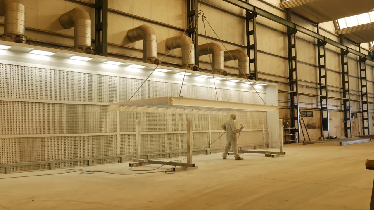 painting station in a metal factory, lights for good lighting and everything in white, painting metal object with a spray gun