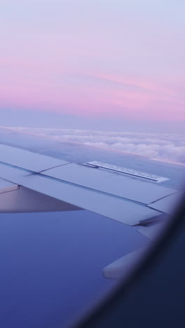 vista desde una ventana de avión del cielo al amanecer con el ala del avión en el tiro en vertical