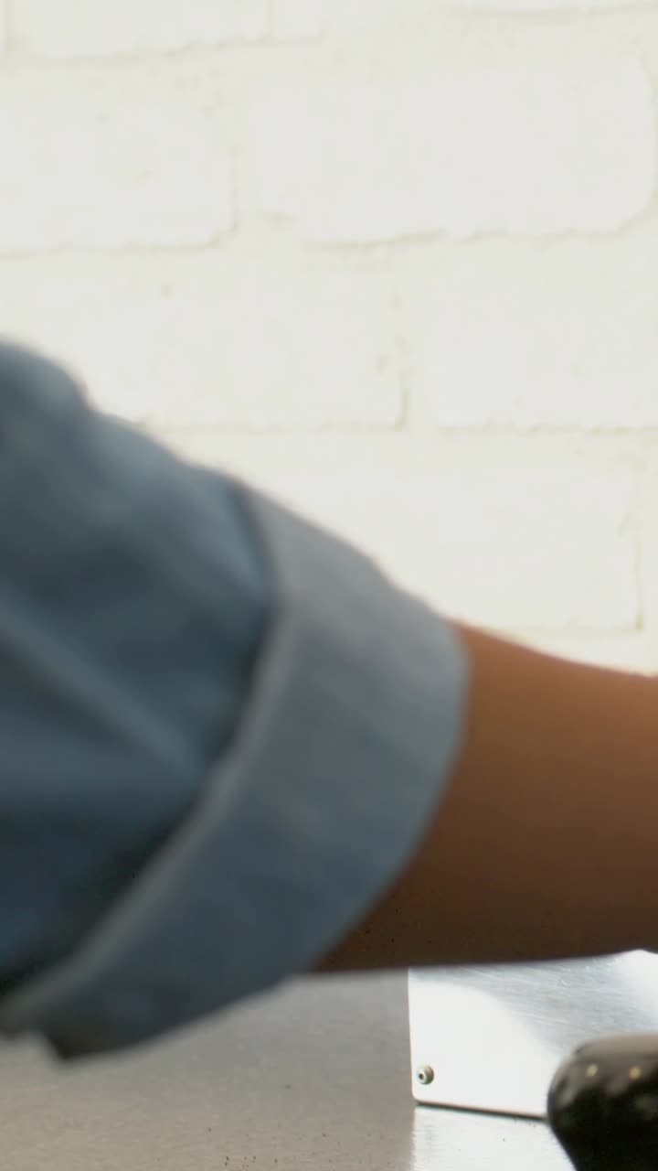 Vertical video: Left arm entering with rolled sleeve, pale watch reaching knob adjusting in kitchen
