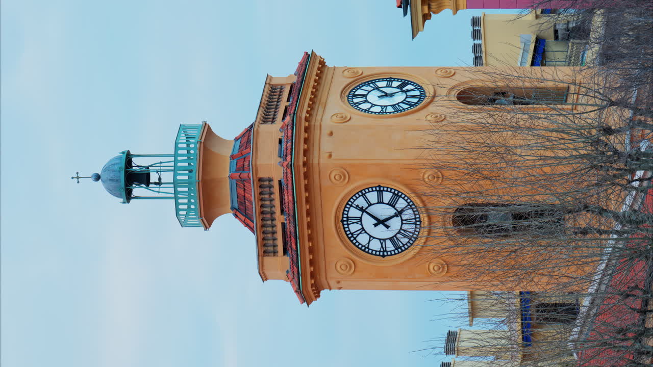 View of an orange clock tower in Nice, France with the sky on the background. Vertical