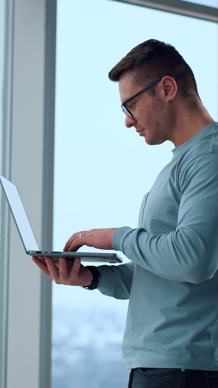 hombre trabajando en una computadora portátil por la ventana