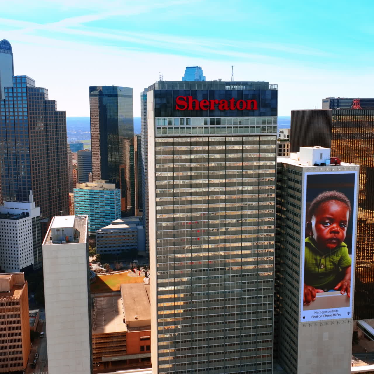 Sheraton Dallas Hotel, edificio con una grande immagine di un bambino e altri splendidi grattacieli nel centro della città. Drone che vola intorno all'architettura a Dallas, Texas, USA.