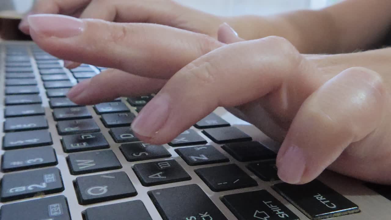 Female hands typing on a laptop, composing an email, report, or digital content.