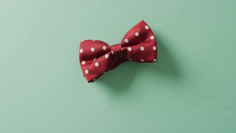 video of red dotted bow tie lying on green background