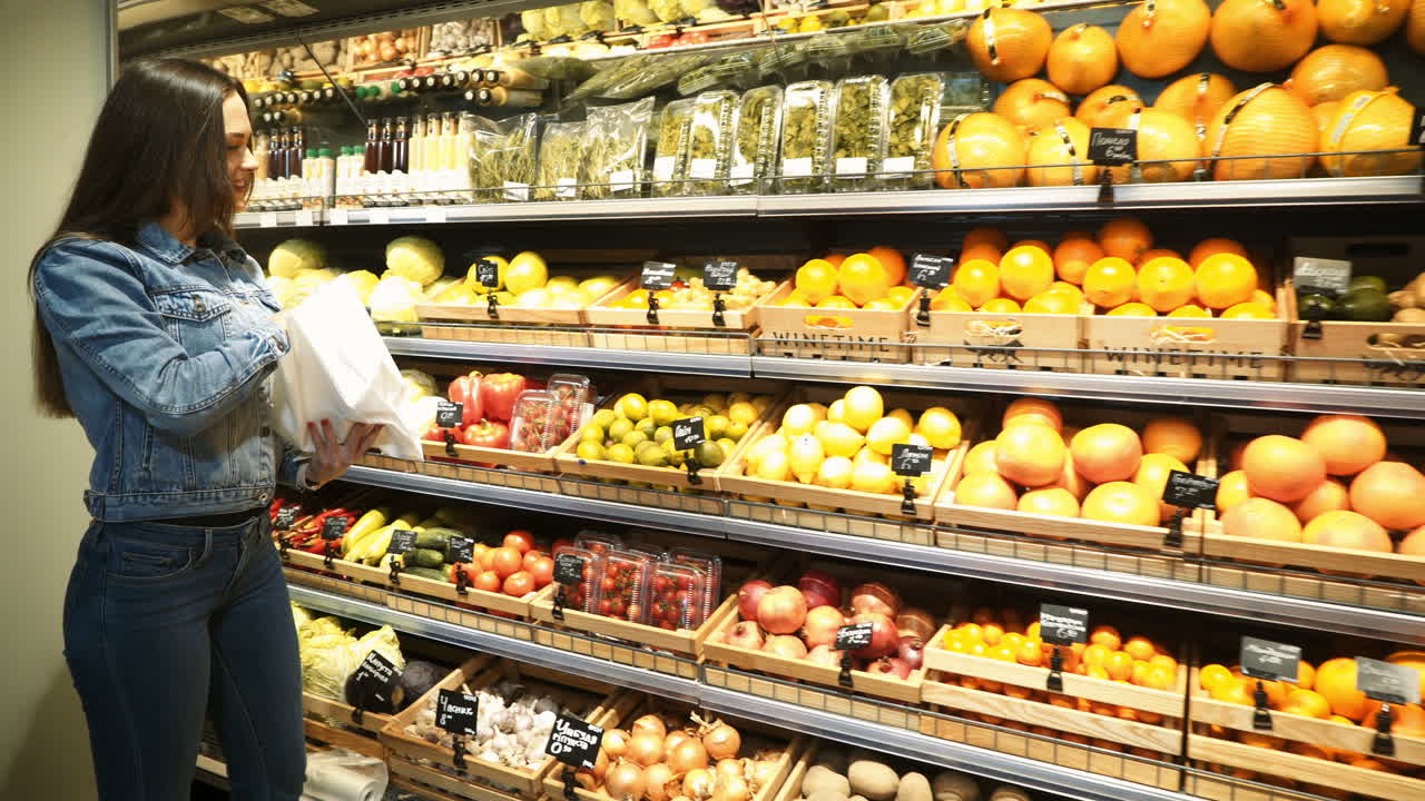 Beautiful young woman shopping for fruits and vegetables in a production department. Grocery store. Supermarket. Healthy lifestyle.