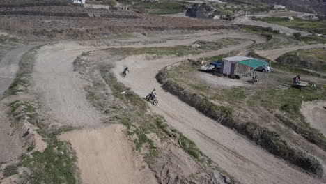 Aerial-shot-of-motocross-riders-on-dirt-track-hitting-a-jump