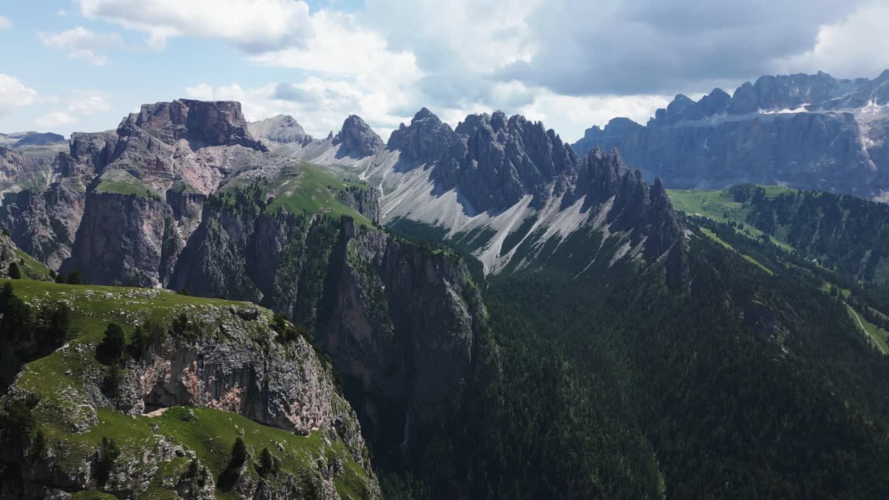Terbang di atas lembah dengan hutan hijau di pegunungan curam dan langit biru, Dolomit, Italia, Eropa, drone