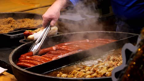 street food. chef prepares sausage for hot dogs and onions, frying them on a large skillet