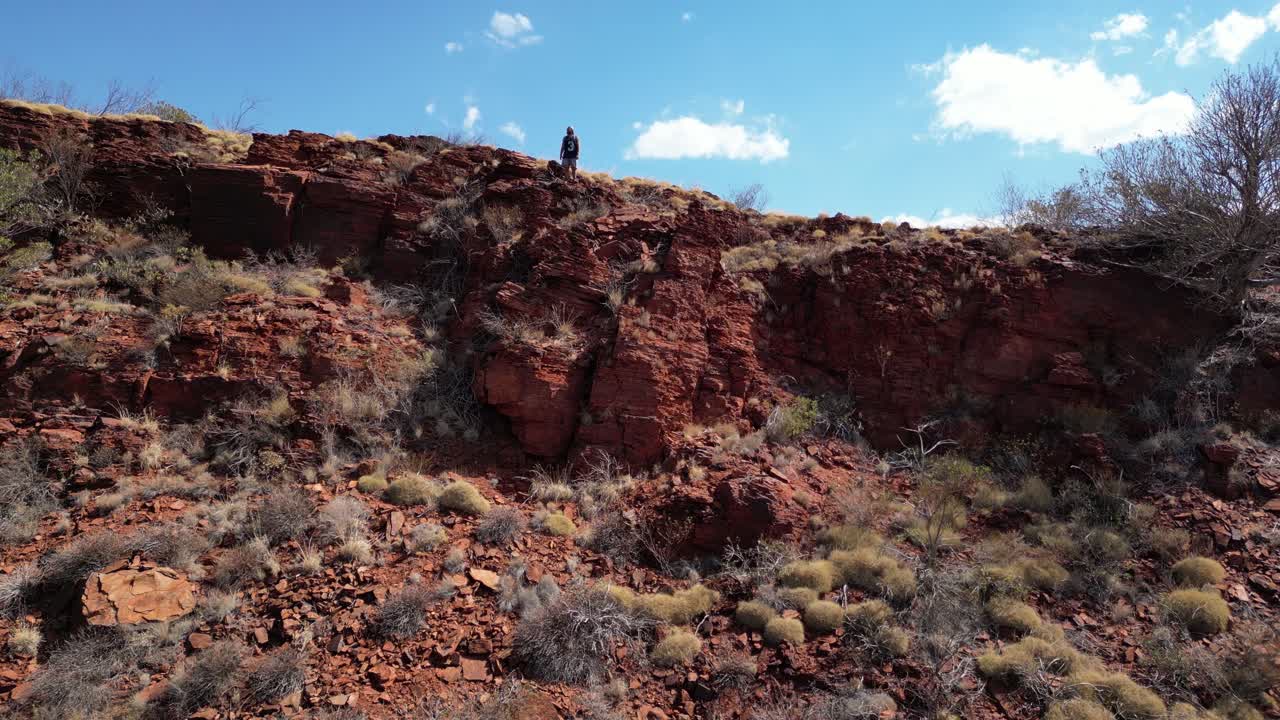 video aéreo de una persona de pie en una formación rocosa en el parque nacional kariini, pilbara, australia occidental