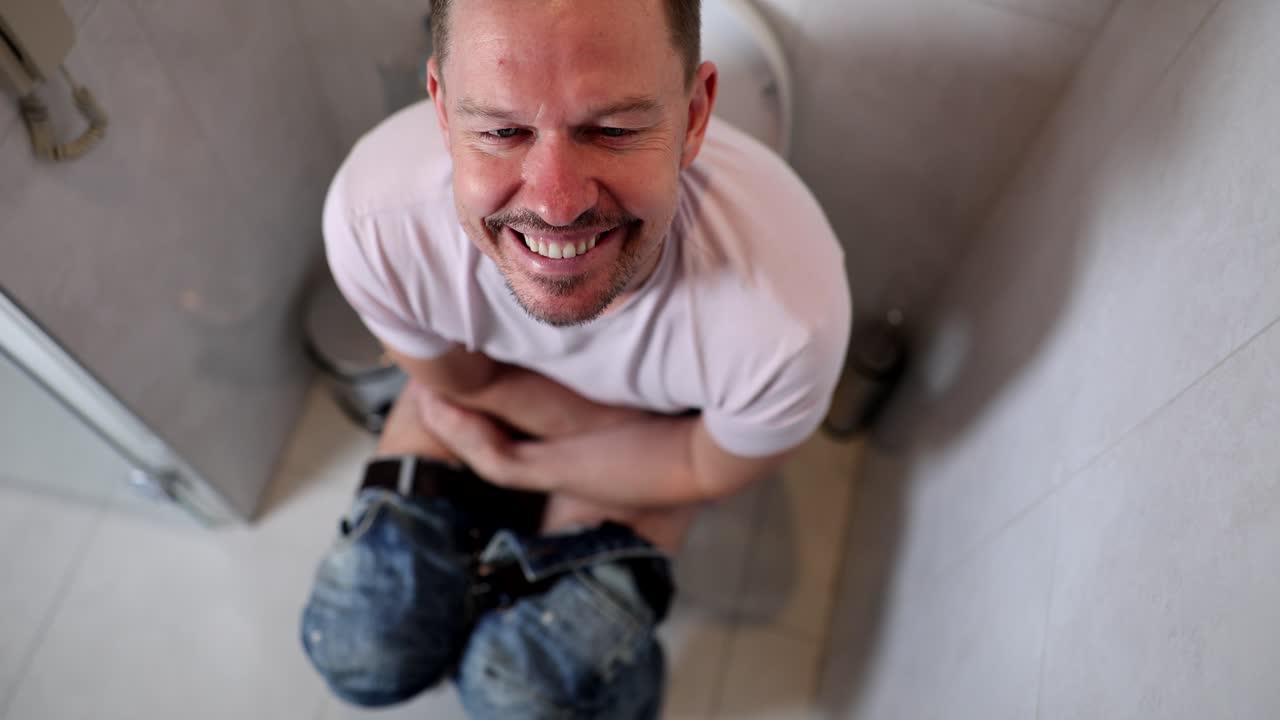 Ritratto di un giovane uomo contento seduto sul gabinetto.
