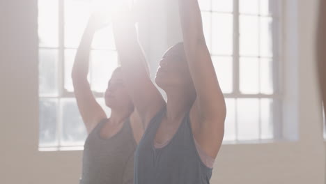 young pregnant mixed race woman in yoga class practicing warrior pose enjoying healthy lifestyle group exercising in fitness studio at sunrise