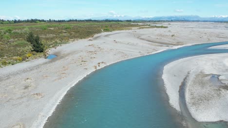 Volando-Bajo-Río-Arriba-Sobre-El-Canal-Principal-En-El-Hermoso-Río-Waimakariri-De-Color-Turquesa,-Nueva-Zelanda---Revelando-Montañas-En-El-Horizonte-Bajo