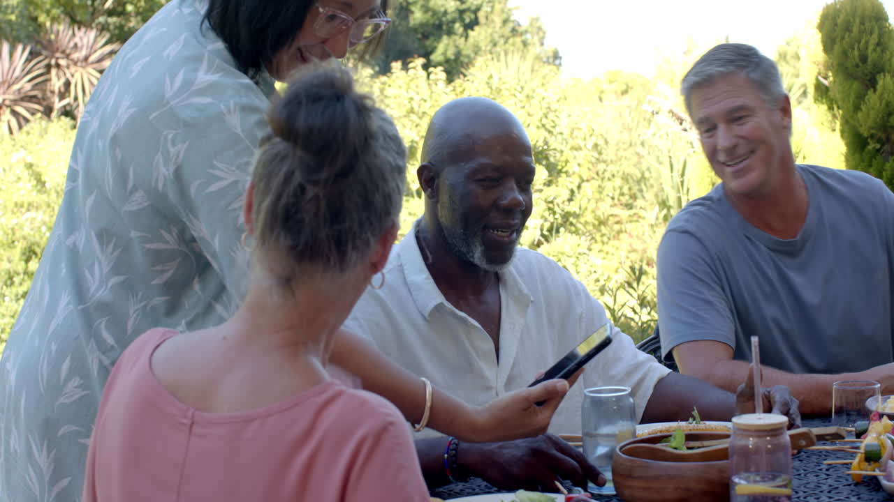 Diverse seniors enjoying in garden lunch, sharing stories and laughter in garden setting
