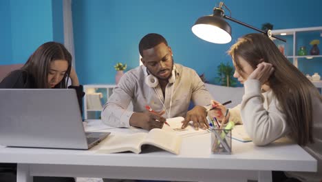 african teenager asking a question to his friend while studying at home.