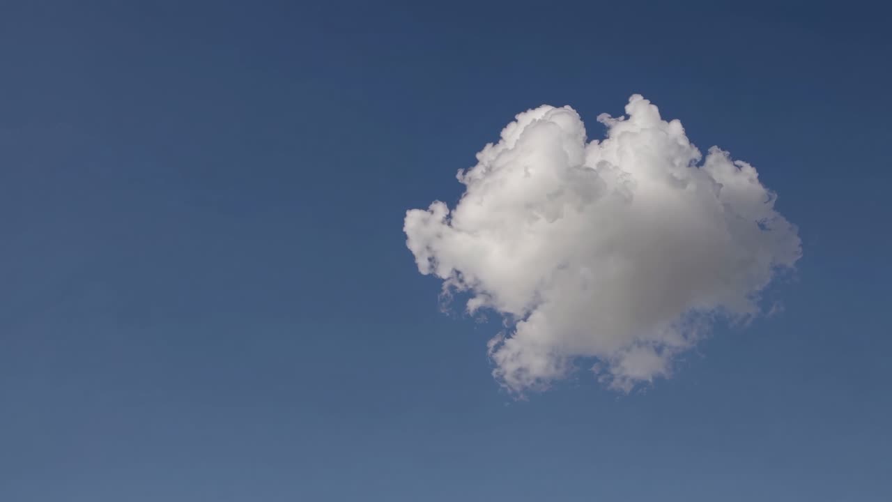 A single fluffy cloud shaped like a heart floats in a clear blue sky