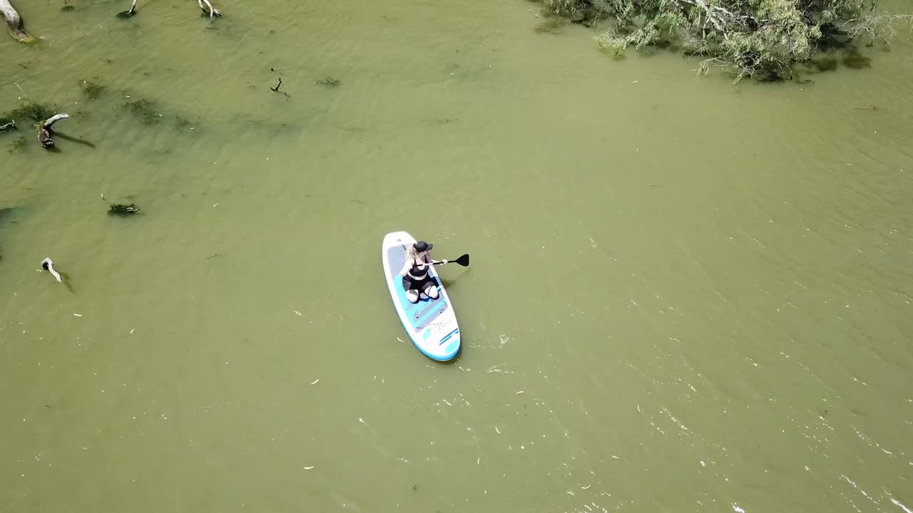 dron aéreo sobre río mujer stand up paddle board remando