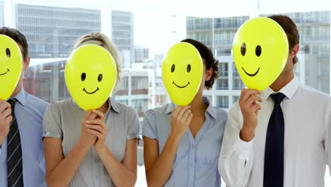 business team holding smiley face balloons