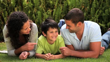 Little-boy-lying-on-the-grass-chatting-with-his-parents