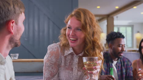 Multi-Cultural-Group-Of-Friends-Sitting-On-Sofas-At-Home-Together-Enjoying-Drinks-And-Talking