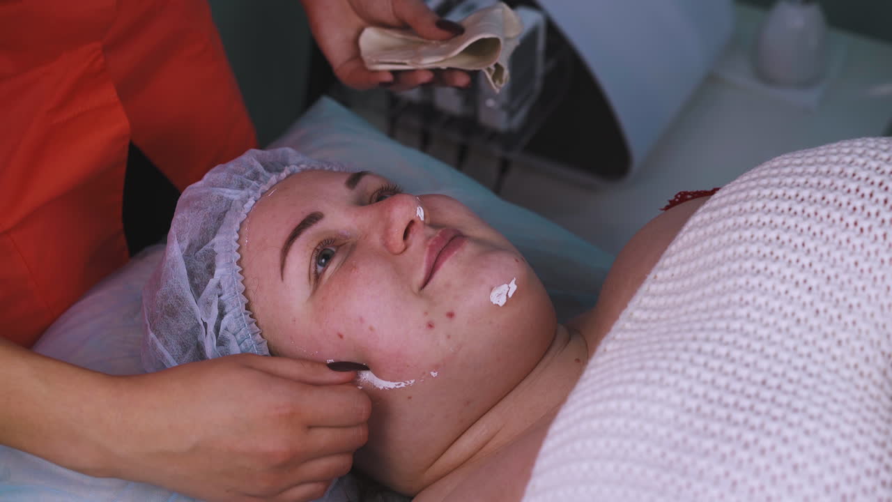 il cosmetologo rimuove la maschera di alginato dal viso di una ragazza di taglia plus
