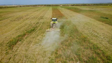 farming tractor mowing weeds on agricultural field in almaty, kazakhstan - aerial shot