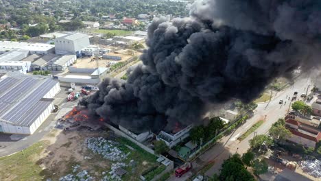 black smoke cloud coming out of warehouse fire, shot with drone