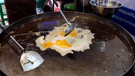 cooking a traditional thai oyster omelet on a hot pan.