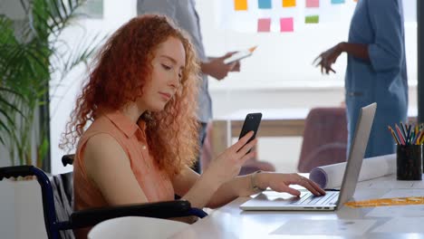 Side-view-of-disable-young-caucasian-businesswoman-working-on-laptop-and-smartphone-in-office-4k